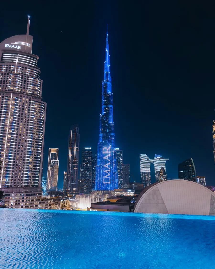 A rooftop pool facing the Burj Khalifa at night