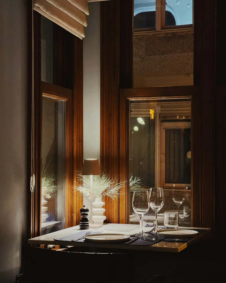 A restaurant table set by a tall window